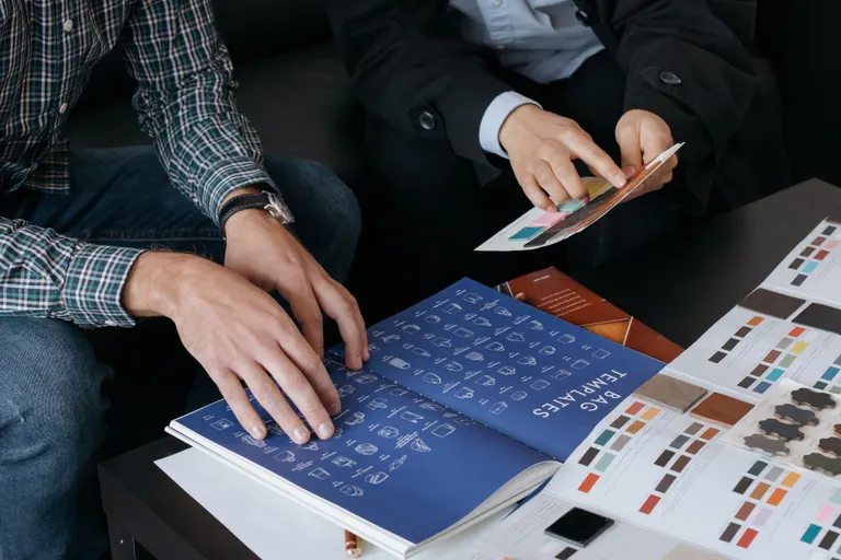 Two designers reviewing brand color swatches and packaging templates at a studio desk